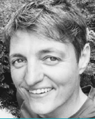 Black and white close-up portrait of a person with short hair smiling at the camera.