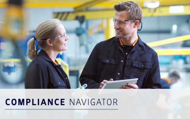 Two people in safety glasses and industrial uniforms have a discussion in a factory setting; one holds a tablet. Text reads "Compliance Navigator.