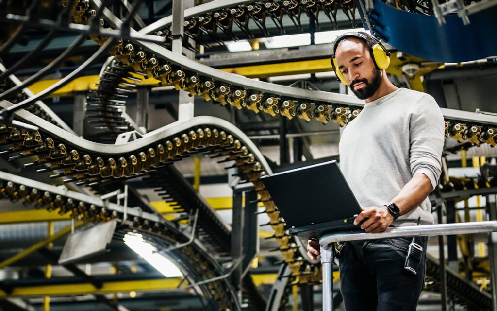 A man stands in front of a laptop computer, focused and engaged in his work.