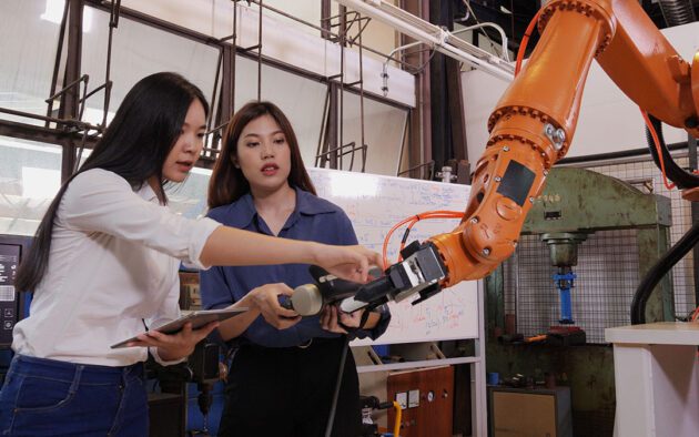 two workers looking at a mechanical shop arm