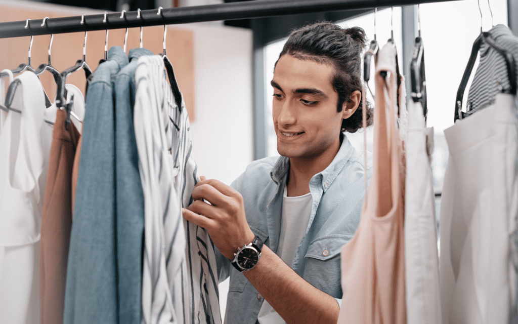Employee looking through a clothing rack in a retail store.