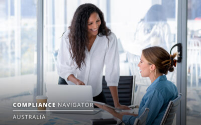 Two people in a meeting room, one standing and one sitting, discussing with a laptop and documents on the table. Text on image reads: "Compliance Navigator Australia.