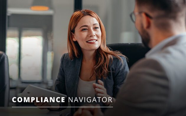 Two people are engaged in a conversation in an office setting. One holds a tablet. The words "Compliance Navigator" are displayed at the bottom.