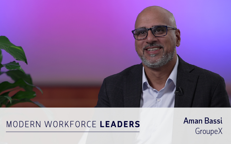 A smiling man in glasses and a suit sits for an interview. Text reads: "Modern Workforce Leaders, Aman Bassi, GroupeX." Plant and purple gradient background visible, highlighting insights on workforce management software.