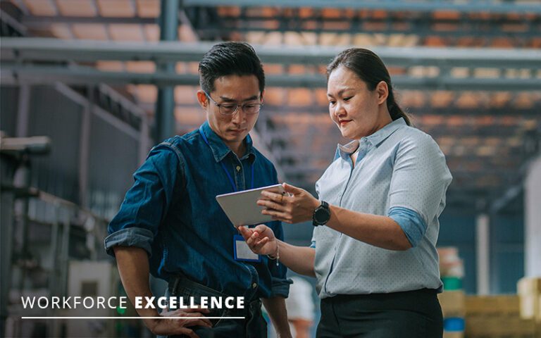 Two people in a warehouse discussing something on a tablet. Text reads "Workforce Excellence.