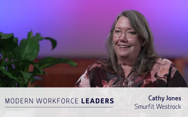 A woman with glasses and long hair sits smiling in front of a plant and gradient background. Text reads: “Cathy Jones, Smurfit Westrock, Modern Workforce Leaders.” Highlighting expertise in workforce management software.