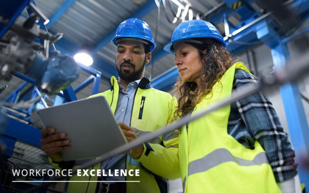 Two workers in safety gear and helmets review information on a tablet inside an industrial facility. Text reads "Workforce Excellence" in the lower left corner.