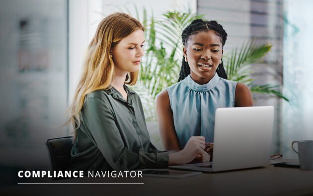 Two women sit at a desk looking at a laptop screen together in a modern office setting. The text "COMPLIANCE NAVIGATOR" appears in the lower left corner.