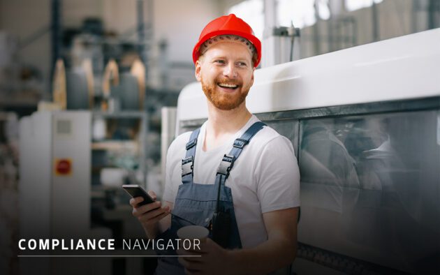 A man in a red hard hat and overalls stands by industrial equipment, holding a smartphone and a cup, with the text "COMPLIANCE NAVIGATOR" on the image, highlighting effective compliance strategies on-site.