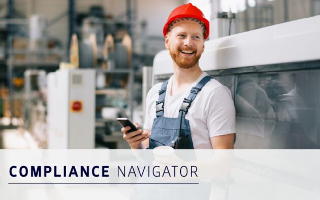 A man in a red hard hat and overalls smiles while holding a smartphone and coffee cup in an industrial setting. Text reads “COMPLIANCE NAVIGATOR,” highlighting smart compliance strategies at work.