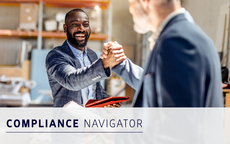 Two men in business attire shake hands and smile in an office setting. Text overlay reads "COMPLIANCE NAVIGATOR.