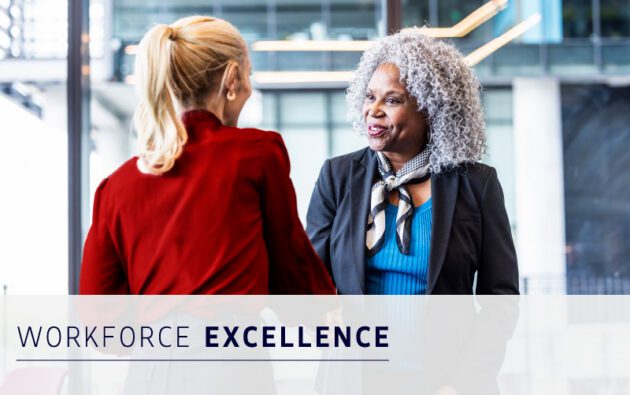 Two professionally dressed women shake hands and smile in an office setting. Text overlay reads “Workforce Excellence.”.
