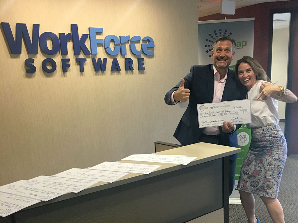 Mike Morini, CEO of WorkForce Software & Alexis Glick, CEO of GENYOUth.org finish signing the grant checks.